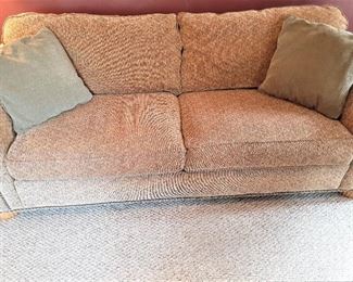 One of the pair of brown tone two seat sofas