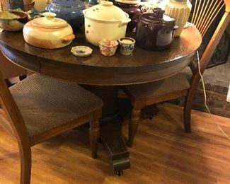 Lovely antique round dark oak table. Also pictured is a great bean pot and pottery collection.