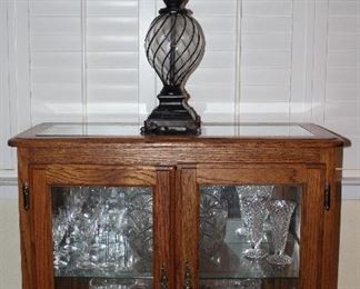 Oak Frame Small Double Door Glass Credenza (30”H x 32”W x 14”D). Show with Metal and Glass Table Lamp