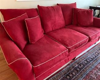 Now $185! ---$250- Super comfortable microsuede vibrant red sofa with four matching throw pillows. No manufacture name. No tears in fabric, but two staining issues- one on the back left arm and the middle cushion has a stain and has been turned upside down. (see all photos)  Has light tan piping. Measures approximately 103.5" long by 42" deep and 30.5" tall in the back and 27" tall in front. The cushions measure 30" deep 26.5" wide. 
