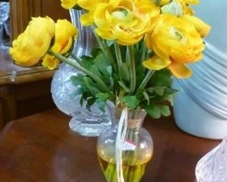 Forever blooming artificial yellow flowers in fake water in glass vase.