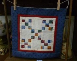 Miniature handmade quilt, approximately 8" square, hung by miniature clothes pins on a cord strung between two post, now offered at $24