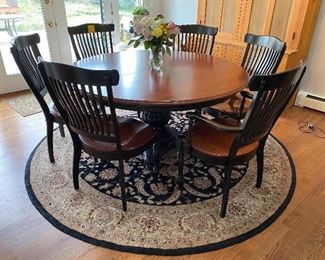 Lot 21. $1200.   60" Round Nichols & Stone Antiquan Pedestal Table and 6 Antiquan Windsor-Style Back Chairs Set (4 side chairs, 2 armchairs) - Could be used in Kitchen or even more formally, as shown, in the dining room.  Super Nice! Seats 6 round and 10  with the leaf.  1 Leaf and Custom Table Pads also included.  Made of Cherry, Seats have  Black Legs and Seat Backs, the pedestal is also painted black.  