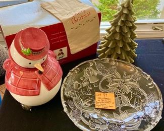 lot 89.  $18.00  Christmas is just around the corner!  JK.  Michel Co. Snowman cookie jar.  (Adorable, with original box, looks new) Angel and Bell Christmas glass platter, 15inches., Christmas Tree Candle and a finger tip towel.  