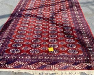 Lot 135. $395. This rug was purchased by the homeowners parents on a trip to the middle east in the 70s.  The fringe has seen better days, but it is hand-knotted and wool. Measures 9'8" by 7'2". Colors are red, navy, and cream. 