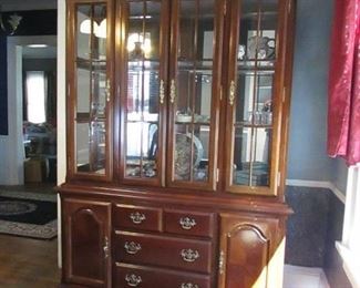 2-piece Queen Anne-style lighted hutch. Cherry finish and glass shelves. 54.5"w X 84"h X 16.5"d. PRICE: $250.00 (any contents of hutch NOT included).