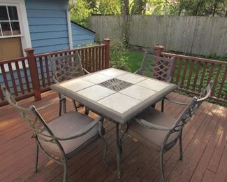 Ornate cast metal and tile patio table with (4) chairs and cushions). Some wear. PRICE: $175.00