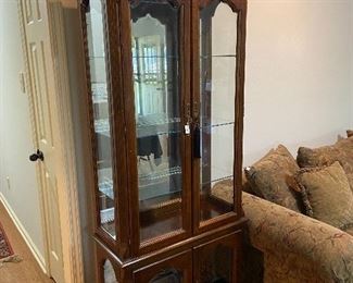 Lighted mirrored-back curio cabinet with glass shelves.