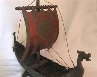Mid Century Denmark Copper/Bronze Metal Viking Ship $250
This mid-century bronze metal Viking ship measures 16” long x 15 ½” high x 7 1/2” wide. It has a dragon bowsprit and a tail of a dragon on the stern. The boat is accented with coins on the top of the center hull. There is a wooden mast with what appears to be a copper and bronze sail with an Eagle or Falcon emblem on it. It sits on a wooden cradle.