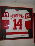 Framed, unsigned, Shanahan Red Wing hockey shirt.