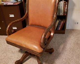 One of two carved wood leather office chairs
