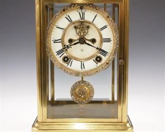 A turn of the century Ansonia "Coral" model crystal regulator.  8-day time and strike movement with two part porcelain dial and Roman numerals, visible escapement with "jeweled" bezel and pendulum.  Molded brass case with beveled glass panels.  Minor wear,running when cataloged.  9 3/4" high.  ESTIMATE $200-300