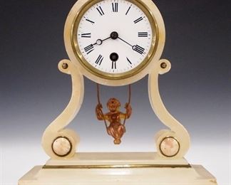An early 20th century French swinging cherub clock by Eugene Farcot.  8-day time only movement with Farcot's "Anchor" trademark having a porcelain dial and Roman numerals.  Onyx case with lyre base and brass detail.  Minor wear, old glued repairs to case, running when cataloged.  9" high.  ESTIMATE $300-400