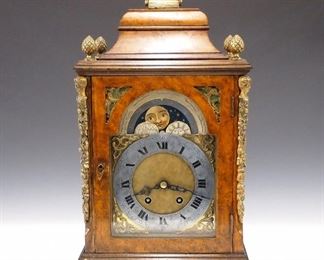 An early 20th century Lenzkirch bracket clock.  8-day time and strike movement with Brass dial and Silvered chapter ring with Roman numerals, surmounted by a painted moon phase indicator dial.  Serial #1 Million, 353355 indicates a date of 1902.  Birds-eye Maple case with molded Pagoda top and Brass handle, cast Pineapple finials and Bronze corner columns with human heads and pierced Brass arched side panels, on a molded base with Brass bracket feet.  Old finish with good color and slight wear, running when cataloged.  17 1/2" high overall.  ESTIMATE $1,000-1,500