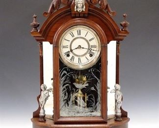 A late 19th century Gilbert "Occidental" model parlor clock. 8-day time and strike movement with papered metal dial.  Walnut case with arched top and Silvered Spelter mounts.  Old finish with some wear, replacements, runs momentarily when cataloged.  23 1/4" high.  ESTIMATE $200-300 