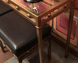 Item 55: Glass top metal table with two bench seats $165 Glass is free of chips or cracks. Seats are upholstered in black vinyl with piping. One stool has four impressions in the vinyl as shown. Good condition.