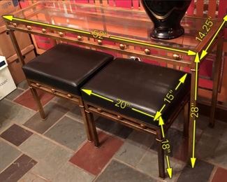Item 55: Glass top metal table with two bench seats $165 Glass is free of chips or cracks. Seats are upholstered in black vinyl with piping. One stool has four impressions in the vinyl as shown. Good condition.