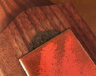Item 63: Vintage Bovano Rosewood Lighter with Enamel on Copper details $15 One of the enameld copper panels has started to slide off of the glue. It isn't sticky, so it must have become too warm at some point. Unmarked lighter sits in top and needs to be reset with something to hold it in place.