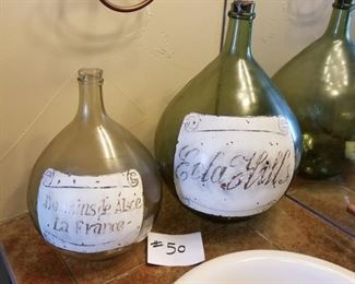 #50 ~$(16) Two round glass bottles- 14” and 17” tall *faded writing*