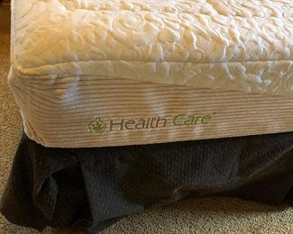 #560- ($50) Queen Bed with health care brand mattress- *price reflects staining on fabric headboard and mattress*