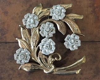 Sweet antique brooch with swirling gold metal leaves featuring sparkly silver flowers with rhinestone centers. 2" x 2 1/4".  $64

