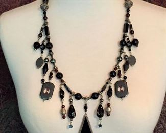 Beautiful artisan-made beaded fringe-style necklace featuring black glass, onyx, garnet, sterling silver, hematite and teardrop-shaped handmade art glass beads. Finished with sterling silver cones and clasp. Length is 25 1/2".  $135
