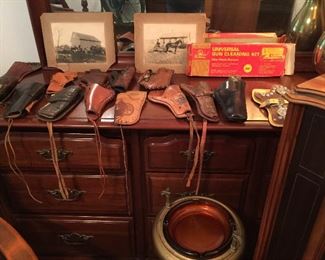 A close look at some of the leather holsters, vintage ash trap in metal stand, photos, gun cleaning kit