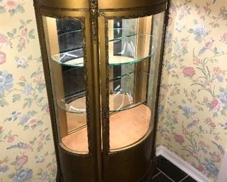 Antique gold display cabinet.  Has curved glass on three sides and mirror on back.  Wood with fancy metal trim.  French cabinet with nate trim and 