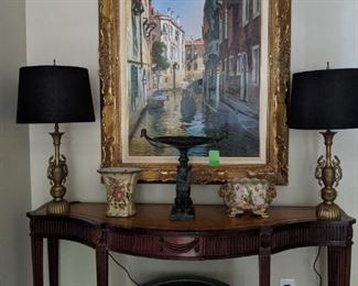 Chippendale Maitland Smith hand-carved mahogany and tooled leather serpentine console, original, nicely framed artist-signed oil on canvas of Venetian canal scene, pair of Asian brass table lamps, Egyptian bronze compote, pair of Asian porcelain vases and large Asian porcelain fishbowl; console table measures 60ʺW × 20ʺD × 32ʺH