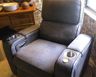 PRICE $325.00 Media Chair. Charcoal, Brushed pebble “leather”. Durable and wipeable microfiber fabric chair.  Electric recliner with cup holders and swing out table top- Interchangeable to right or left arm.  USB charging, Blue LED under chair lightIng for illumination while watching a Movie!!! Just Add Popcorn;-)
Super comfy and nice.
Measures: 42”High • 38”Wide • 35”Deep 
Item#65493