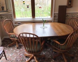 Huge oak pedestal table with extra leaves. Also available are 4 upholstered  swivel chairs on casters. See next picture.