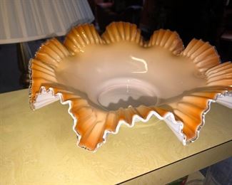 Ruffled porcelain orange lined bowl, maybe Fenton if so it is art glass.  This piece is thinner and has a different ring to it. 