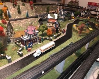H O scale Train village with four tracks and utilized Christmas village buildings, has street scenes and four tracks