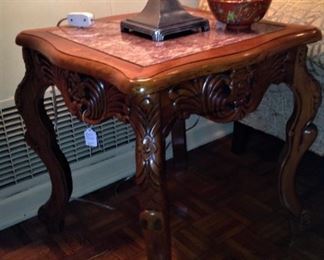 One of two carved, marble-topped end tables