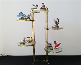 9 Lenox porcelain birds and 1 Capodimonte Rosebud candle holder. Stand is metal with 5 round glass shelves, approx 30" H x 24" W. Metal on stand has some wear. Birds in excellent condition.,