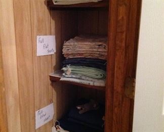 Closet and table full of sheets and pillowcases (king, green, full and twin)