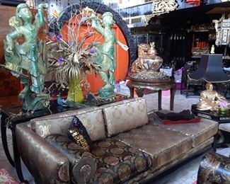 One of two sofas with silk upholstery. Thai dancers and floral arrangements lend a theatrical air to the space. Lamp with gold figure and black shade is one of three pairs still available.