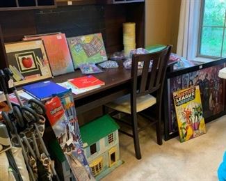 Back bedroom: Large desk with shelf hutch, chair, and a filing cabinet.  Baby Pack n' Play, umbrella stroller, vintage doll house, Justice League Art, two scrapbooks, art kit, more Lego sets.