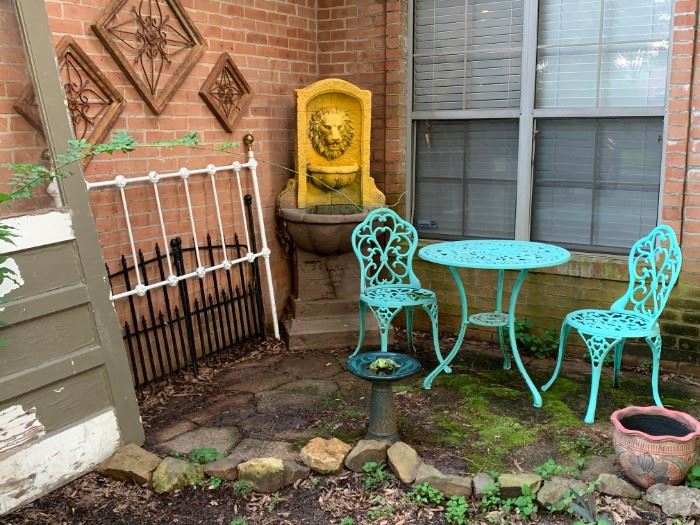 Front Entrance:  More outdoor decorations.  An old door, headboard, metal and wood wall art, garden gates, Lion head fountain, three piece table set, bird bath, flower pot.  Not pictured, old wooden school desk, broken tile mosaic decorated top flower stand, birdfeeder on a pole, shepherds hook.