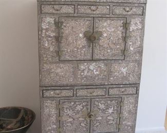 A Korean stacking chest in black lacquer inlaid with mother of pearl featuring birds and animals in  a landscape setting.