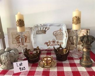 Lot 903. $65.00.  All in for the King and Queen! 2 crown wall art, 1 gold and white platter, 2 crown candle holders, 2 crested candles on clear glass candlesticks, 1 crow statues, 1golden teacup, and saucer, 1 chess pc. (13pc).