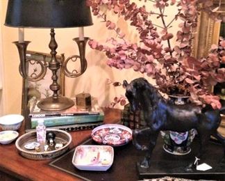 A solid brass bouillotte lamp with French horn motif topped with a black  shade. 