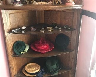 Hard to find bowed glass corner cabinet, Inside are vintage head gear. On top are Victorian pieces and antique hatstands!