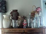 Old pottery pitchers and churn, old water jars, milk bottle, hand-made basket, and Coca-Cola items.