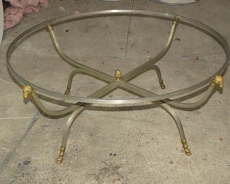 ITEM 4  ==Jansen style brass or bronze Rams head and hoof, pineapple finial in center, glass top coffee table. 39"diameter, widest point 42" to heads 17 1/2High  $450.00