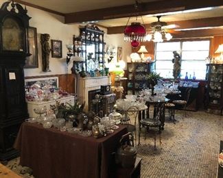 The Ice Cream Parlor with EAPG Early American Pressed Glass, another beautiful antique grandfather clock, mirrored display shelf, ruby red oil lamp chandelier, Gone with the Wind electrified oil lamps, ice cream parlor metal chairs and tables.