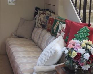 Long couch, Christmas pillows, silk flowers, framed butterflies and Asian end table.
