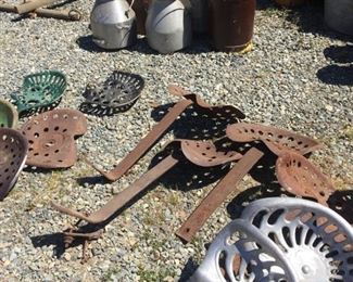 lots of tractor seats and milk cans
