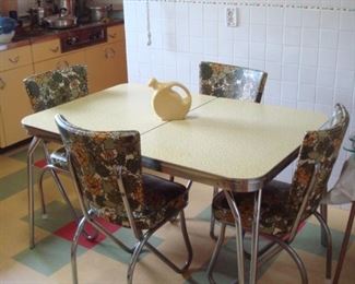Kitchen: A 1950's kitchen set has a yellow/black top (a closer photo follows) and four floral chairs. There is a self-storing leaf inside the table.