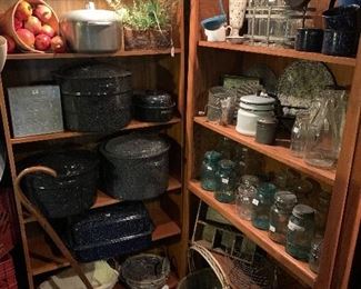 A quiet corner of the pantry showing enamel roasters, other enamel pieces, antique canning jars, antique milk bottles and other supplies